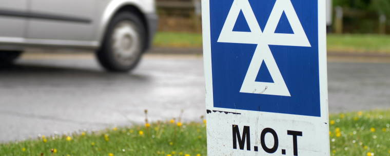 Van Driving Past a Sign at an MOT Test Centre