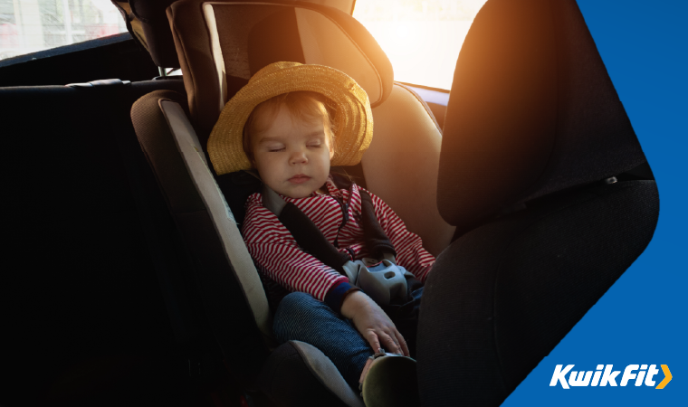 A child sat in a car seat in the back of a car