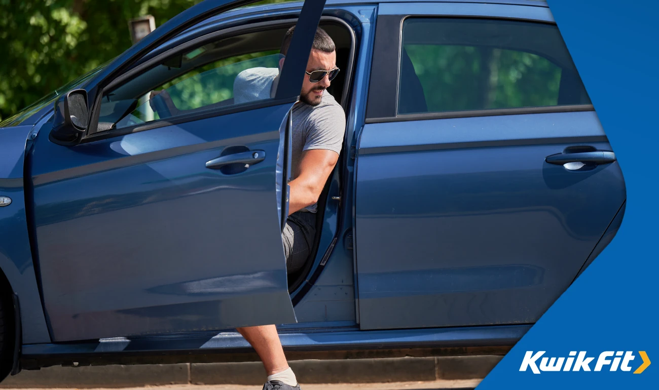 Person with sunglasses on stepping out of a blue vehicle.